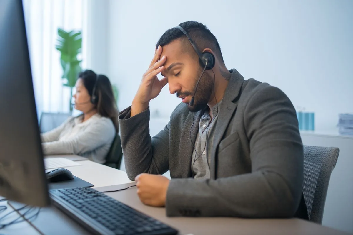 Agente de atención al cliente agotado con cascos y múltiple consultas sin responder